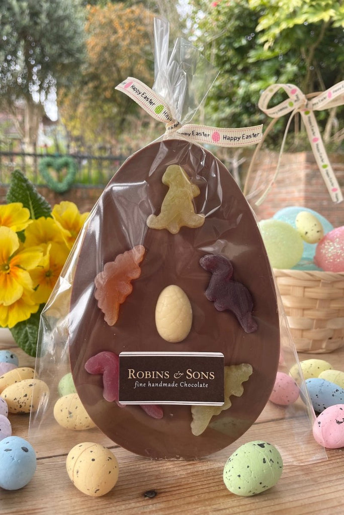 Dinosaur Easter Egg. Oval shaped milk chocolate bar topped with 5 fruit flavour dinosaur shapes and a white chocolate mini egg