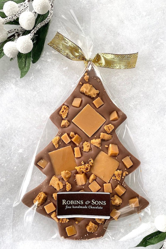 A chocolate Christmas tree shaped bar with vanilla fudge and lotus biscuit pieces, decorated with a gold ribbon bow